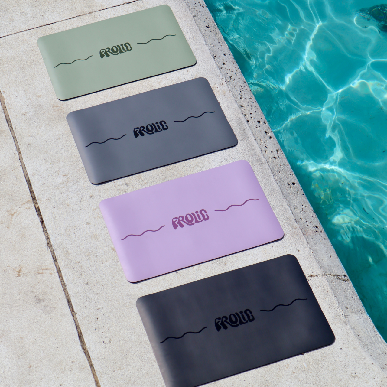 Frolic Balance Base mats in Ebony, Lilac, Sage, and Charcoal laid side by side beside a pool, highlighting full color range and outdoor training versatility